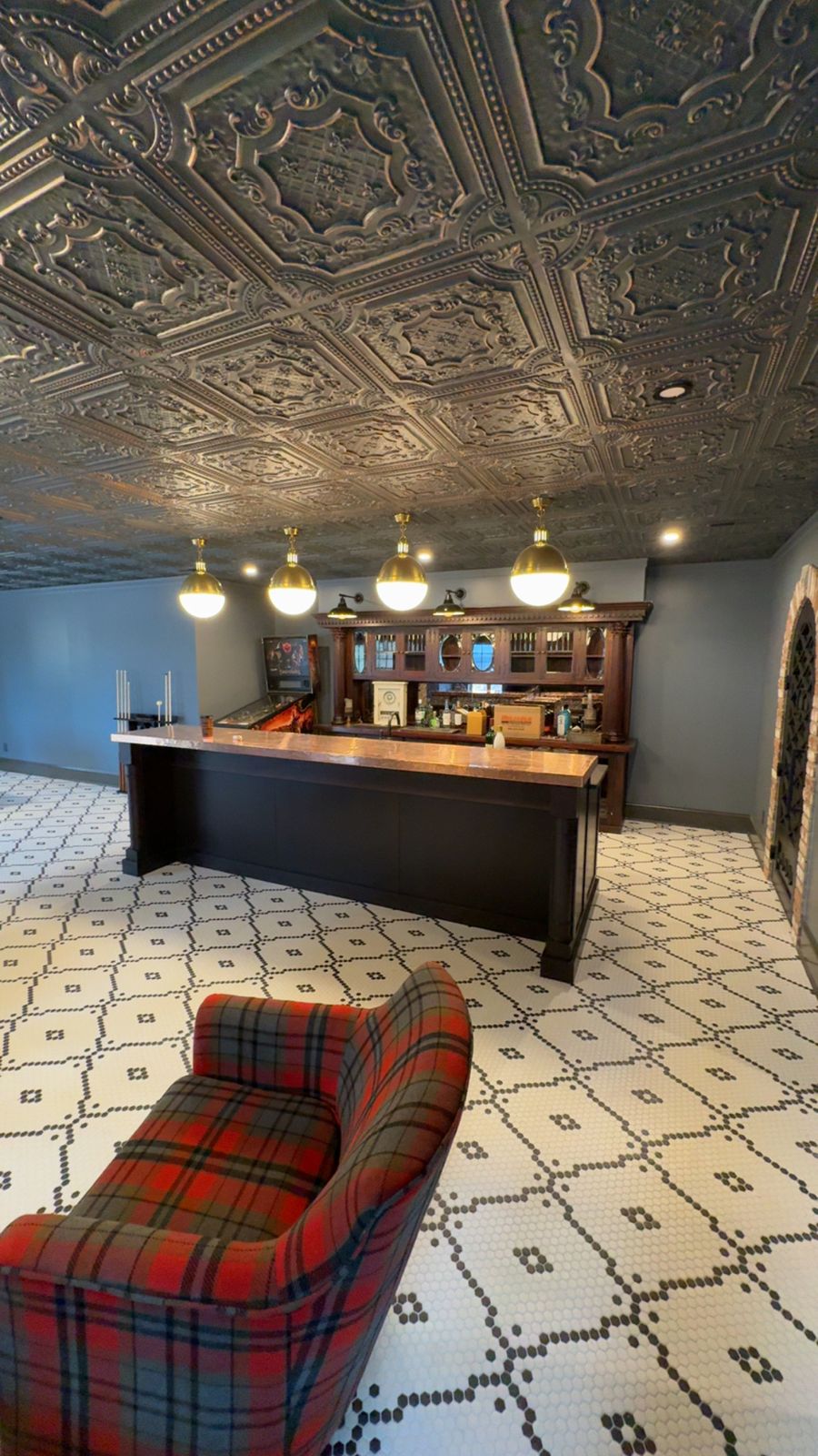 Basement bar with a tin ceiling, brass pendants and hex tile floor