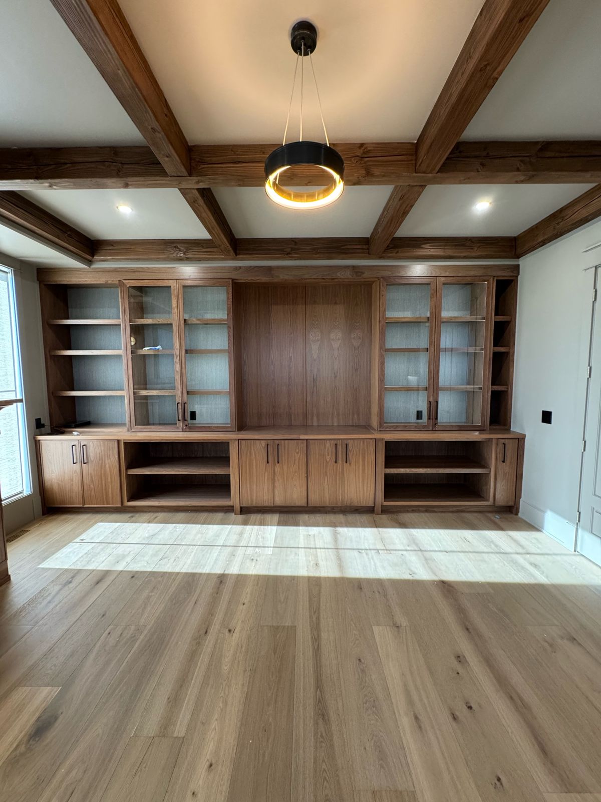 Coffered home office with a black and gold ring pendant and walnut built-ins