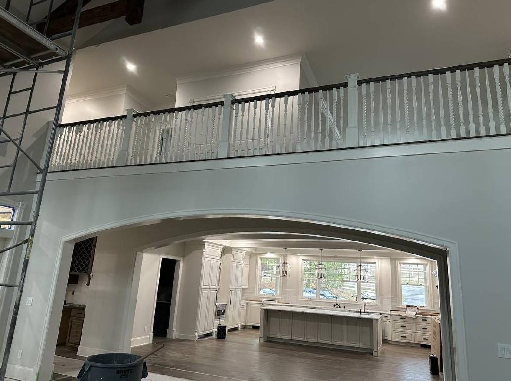 Custom home interior with arched opening and balcony railing during construction