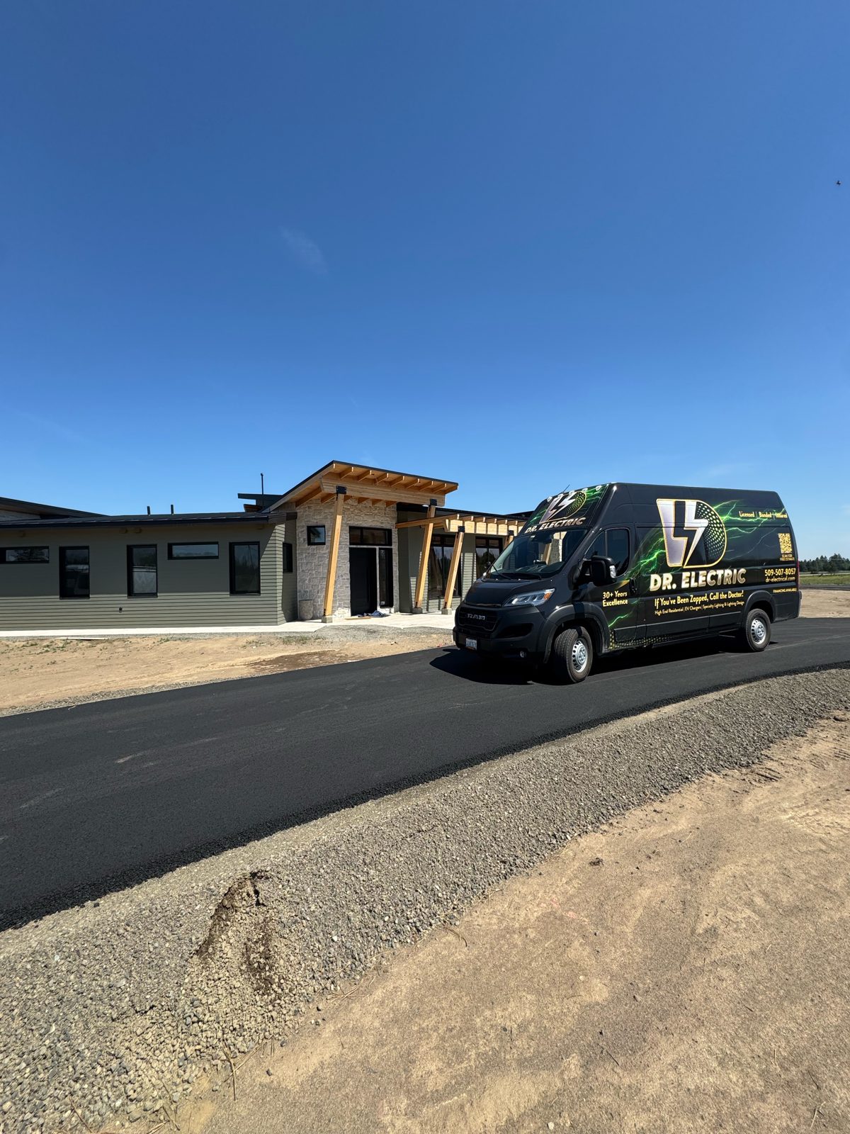 Dr. Electric branded work van parked in front of a newly built custom home under blue sky