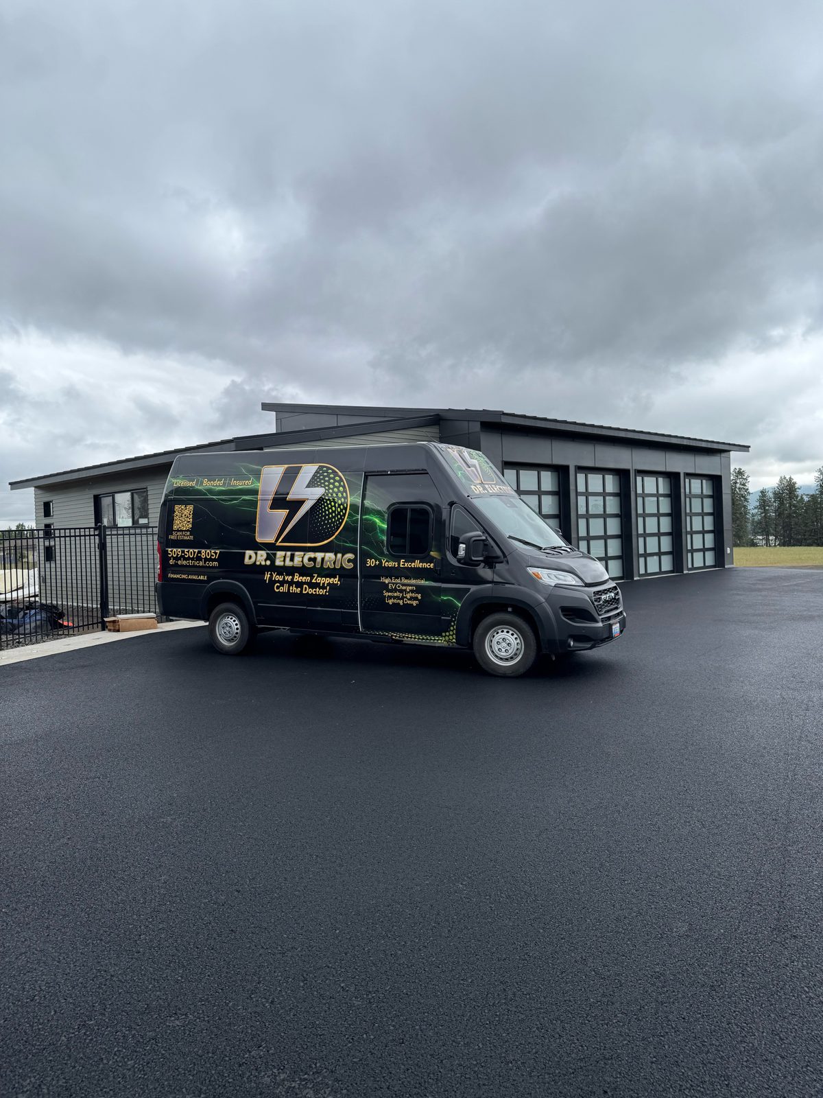 Dr. Electric work van parked in front of a modern shop with glass garage doors