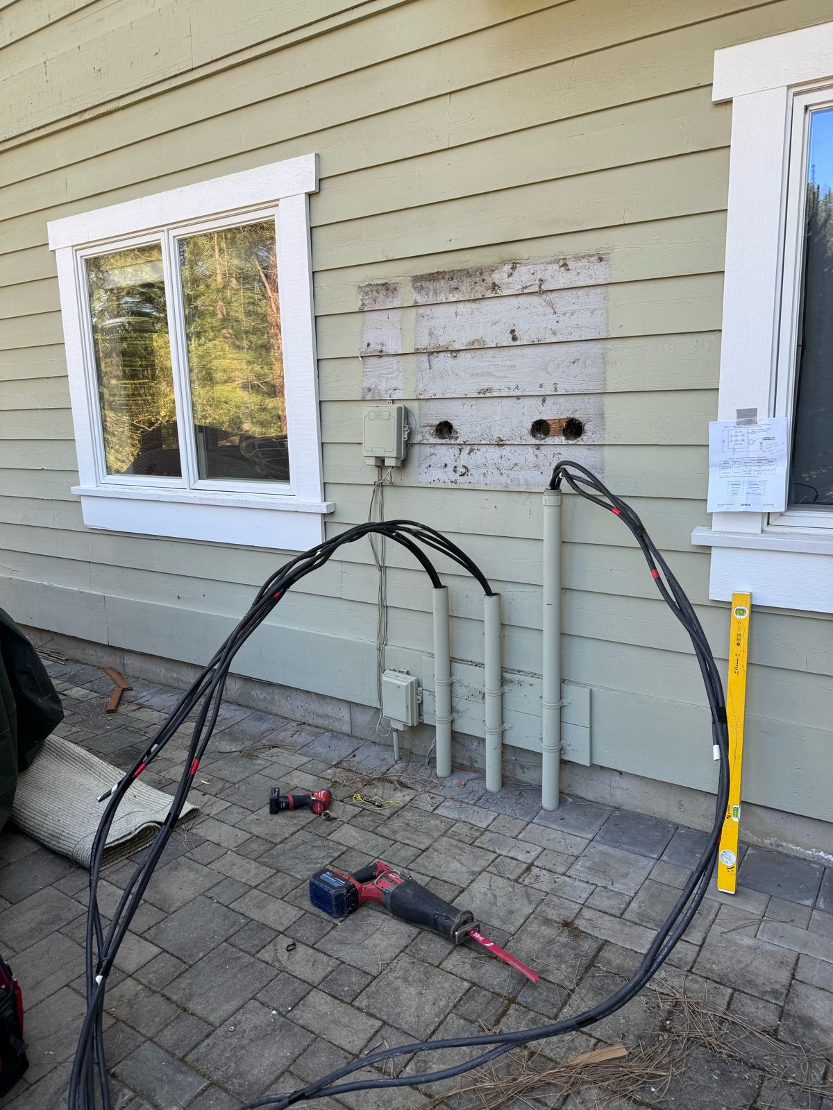 Old electrical service removed from a home exterior, leaving the conduits and service cables exposed