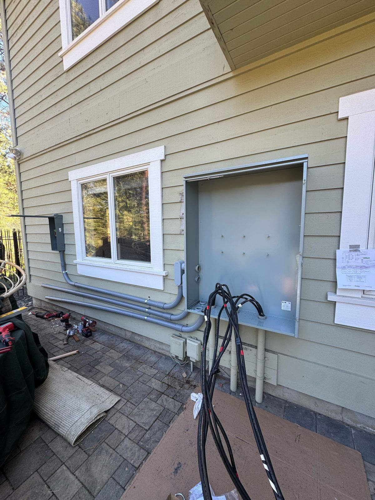 New large electrical service enclosure mounted on the home exterior during a service upgrade