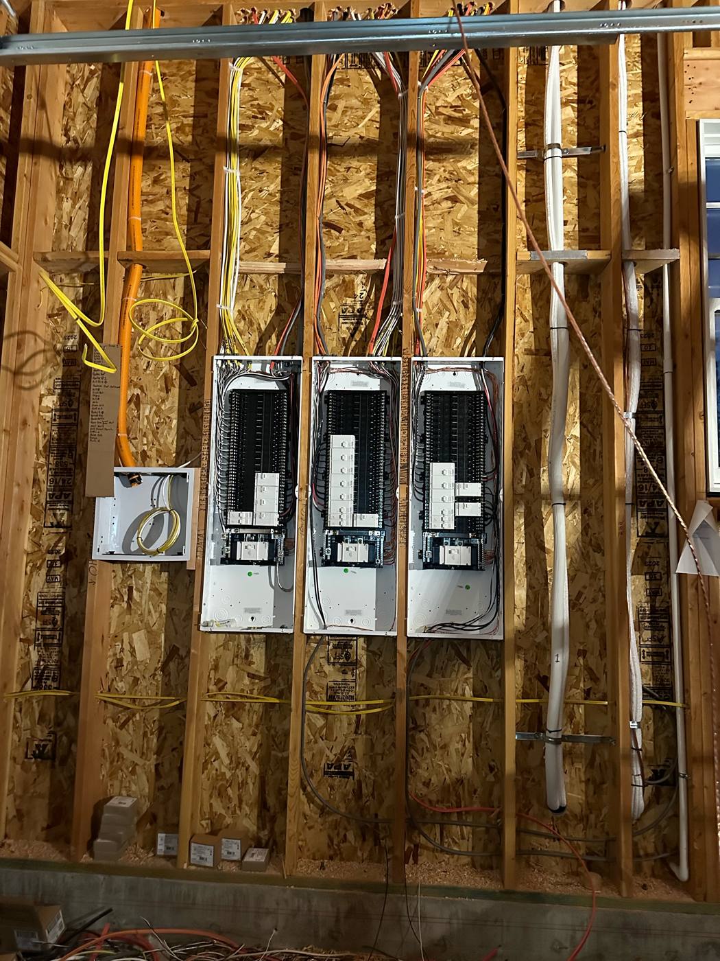 Three electrical panels roughed in and neatly wired with covers off